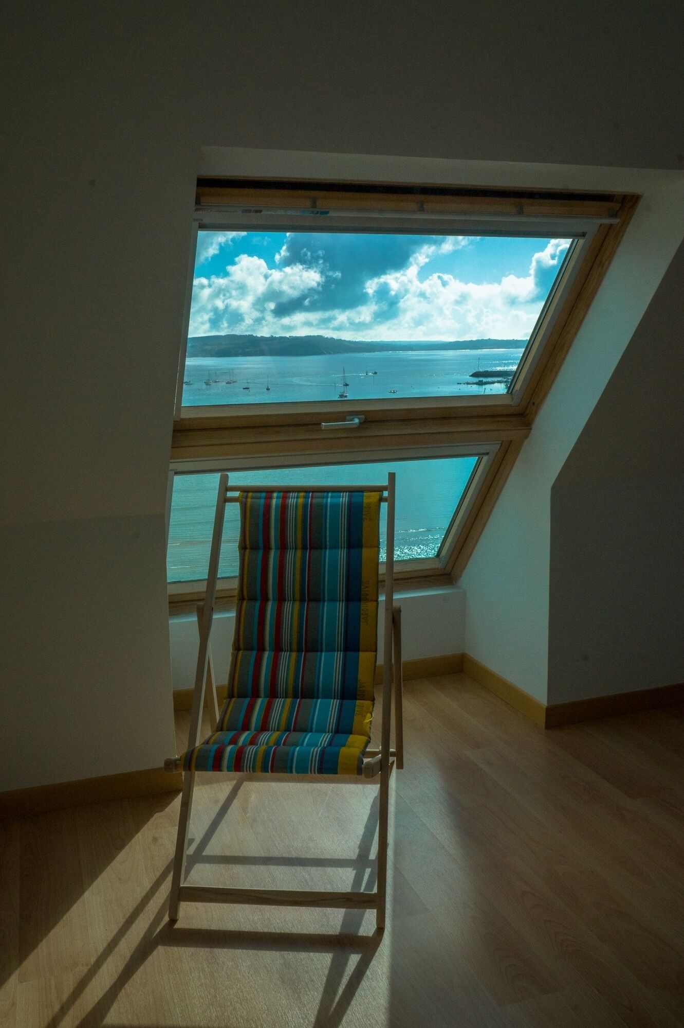 Ein Zimmer mit Oberlicht und einem farbenfrohen Streifenstuhl.