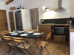 Eine kompakte Küche mit Esstisch für vier Personen, Holzstühlen, fest eingebautem Backofen und Herd.