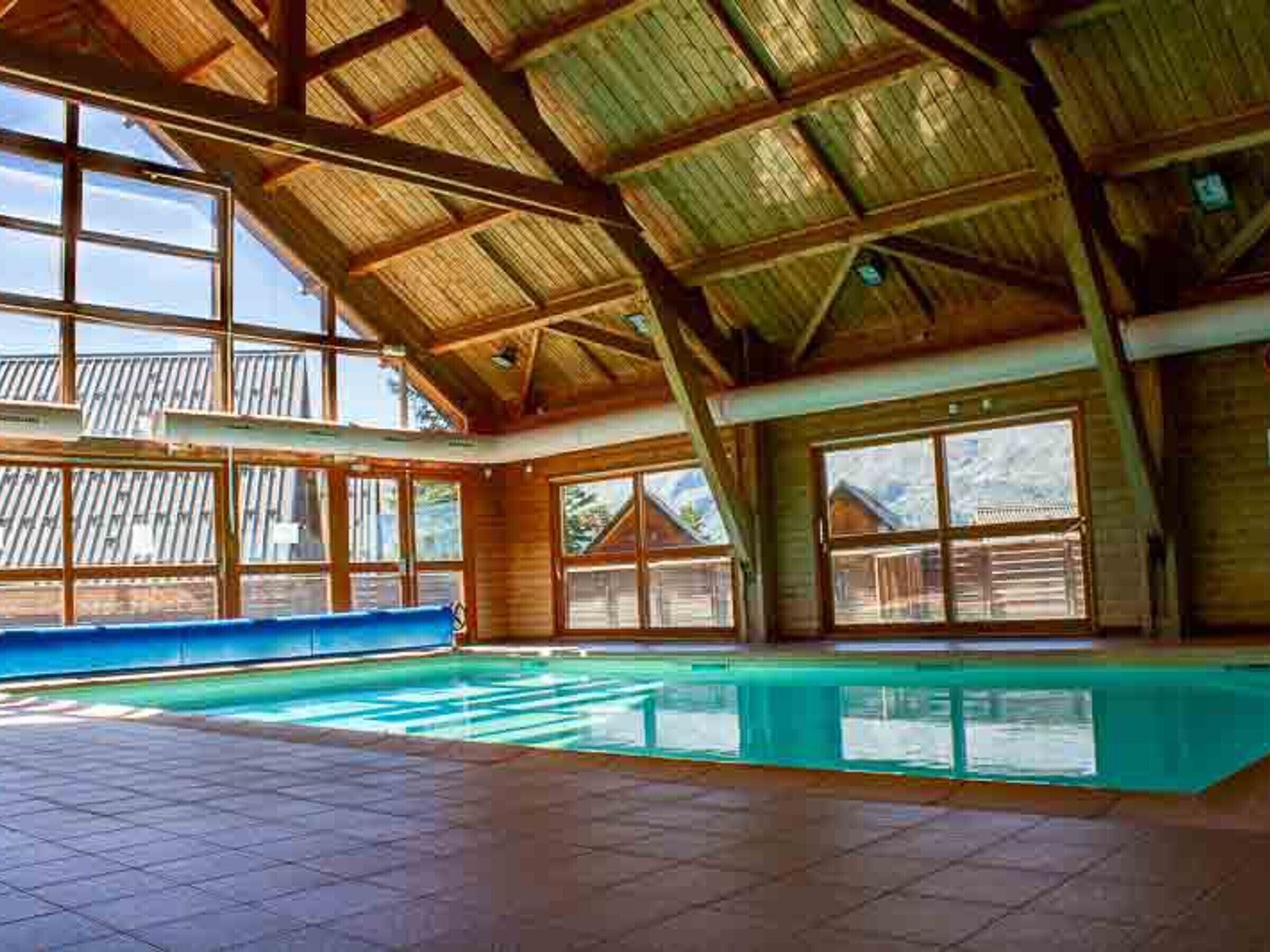 A large indoor swimming pool with a high ceiling and large windows.