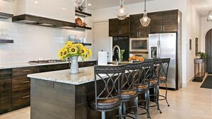 A modern kitchen with dark wood cabinets, a granite countertop, and a central island with bar stools.