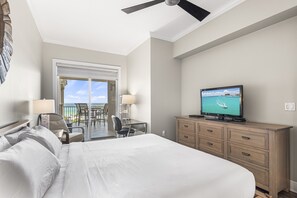 Habitación de hotel con cama, escritorio, televisión y balcón con vista al océano.