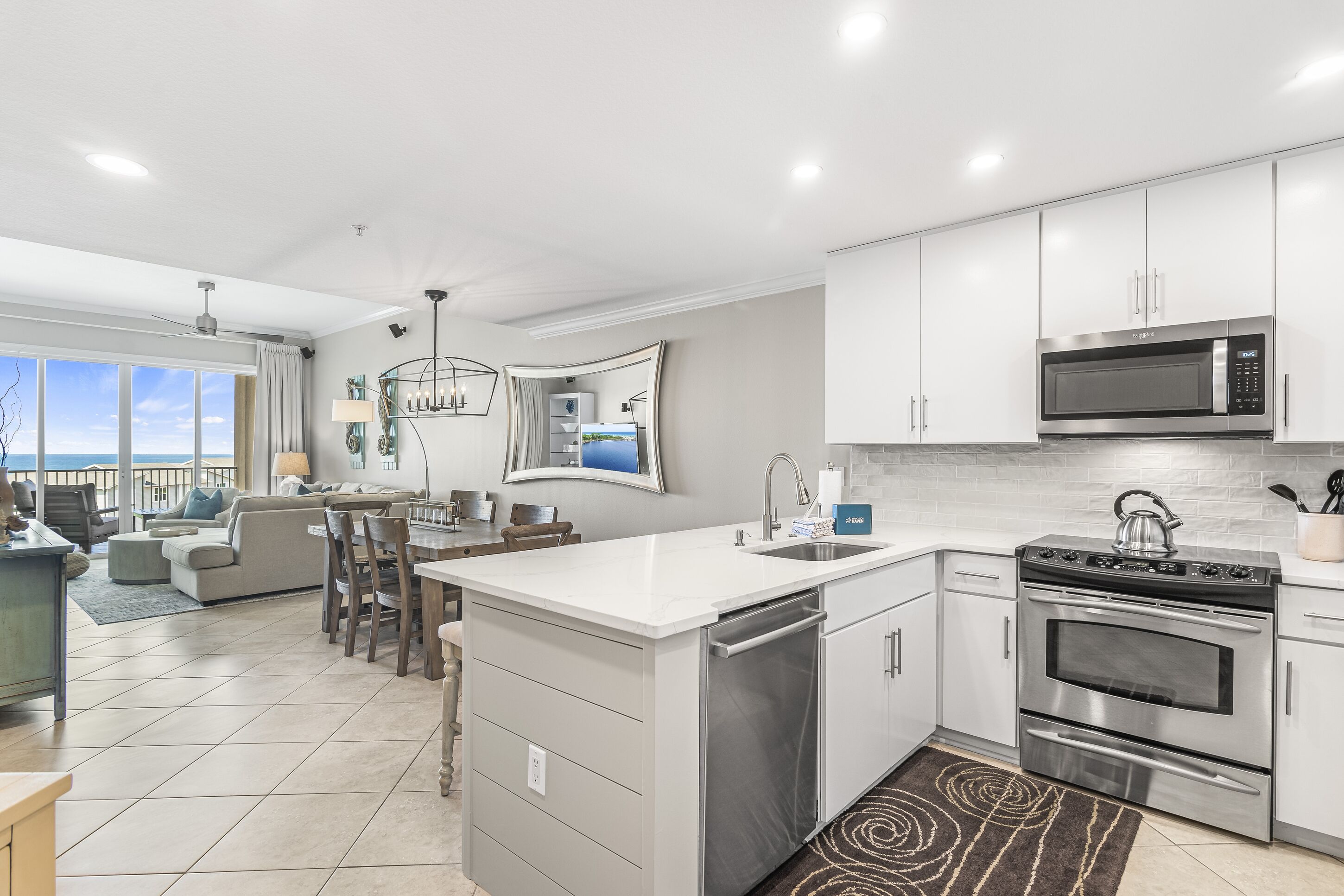 A modern kitchen with stainless steel appliances, a central island, and a view to the outside.