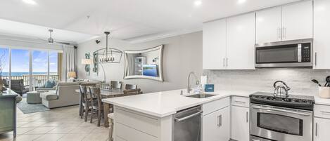 A modern kitchen with stainless steel appliances, a central island, and a view to the outside.