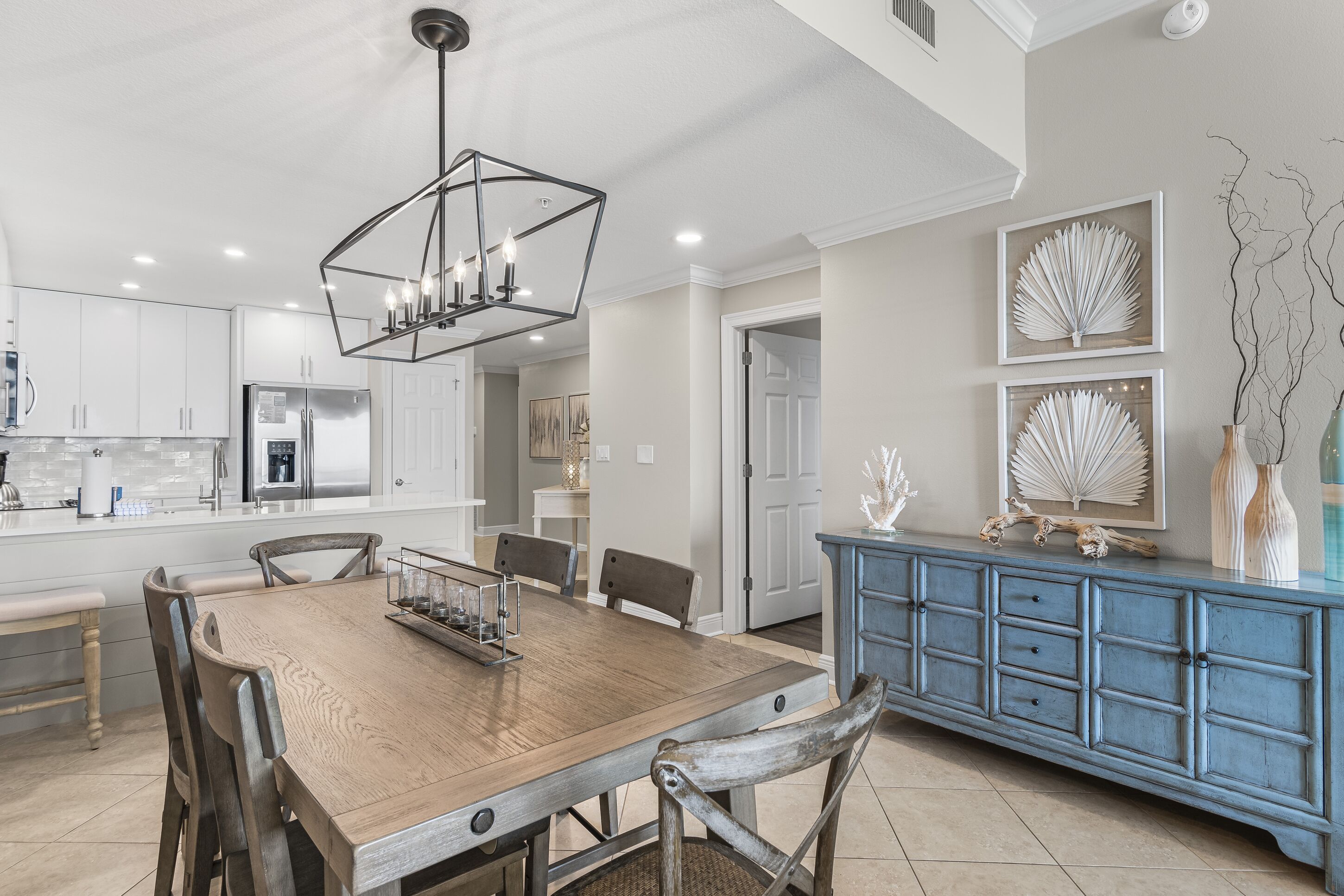 A modern kitchen with white cabinets, a wooden dining table, and a blue cabinet with decorative items.