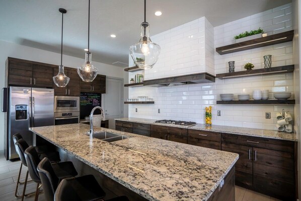 A modern kitchen with granite countertops, stainless steel appliances, and pendant lighting. - Arcadia 31 🧡 Private Hot Tub * Arcade Gaming Room * Sleeps 28! (Santa Clara)