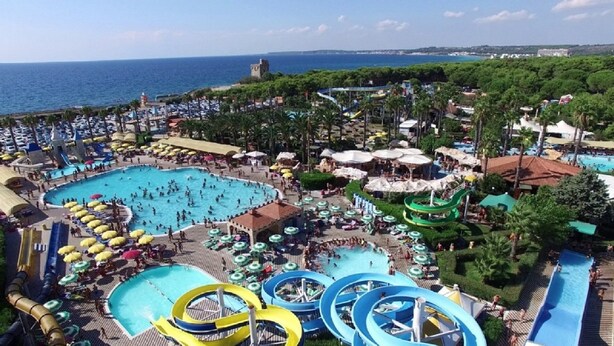 Een resort met meerdere zwembaden, glijbanen en strandparasols.