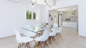 A modern kitchen with white cabinetry, a glass dining table, and white chairs. - DONES D'AIGUA 11 - Villa with sea views in Urb. S'Estanyol (Colonia de Sant Pere). Free Wi (Artà)