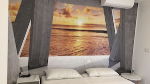 Una camera da letto con un letto, cuscini, un comodino e un condizionatore d'aria a parete.