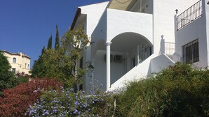 Un edificio bianco con piscina, immerso nel verde e sotto un cielo azzurro.