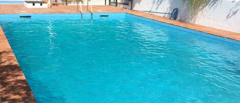 Ein rechteckiger Swimmingpool mit klarem, blauem Wasser, umgeben von einer gefliesten Liegefläche.