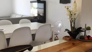 Una cucina moderna con un piano di lavoro in legno, piano cottura integrato, sedie bianche e un tavolo da pranzo.
