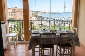 A balcony with a table set for two, overlooking a marina with boats. - Homerez - Apt near beach & pool (Six-Fours-les-Plages)