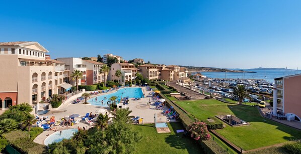A resort with a central swimming pool, multiple balconies, and a marina. - Homerez - Apt near beach & pool (Six-Fours-les-Plages)