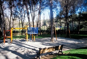 A playground with swings and a bench in a park. - Homerez - Apt near beach & pool (Six-Fours-les-Plages)