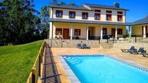 Une maison à deux étages dotée d’une piscine, d’un espace extérieur aménagé et d’une pelouse bien entretenue.