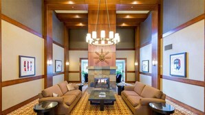 A spacious lobby with a central fireplace, two sofas facing each other, and a patterned carpet.