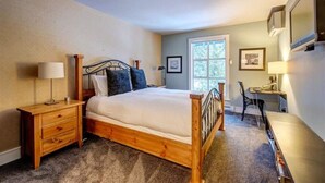 A bedroom with a wooden bed, bedside tables, a desk, and a chair.