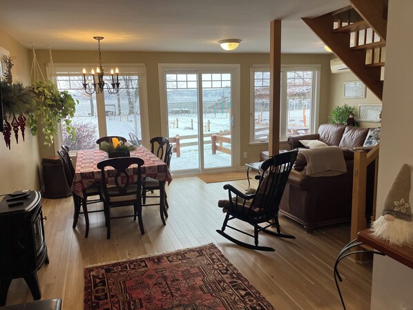 Un coin repas avec une table dressée pour quatre personnes, un fauteuil à bascule, un canapé et un escalier.