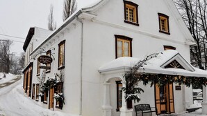 A white building with a sign reading "Chocolatier de l'Hotel." - THE HOUSE OF THE RIVER WITH GREAT WATERS #CITQ 299191 (Saint-Laurent-de-l'Île-d'Orléans)