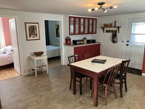 A compact living space with a dining area, kitchenette, and a bedroom.