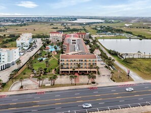 An aerial view of a hotel with multiple buildings, a swimming pool, and a road with cars.