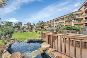A hotel with a pool, a wooden deck, and a view of the surrounding landscape.
