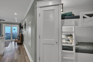 A bedroom with a bunk bed, a white wardrobe, and a view of the balcony.