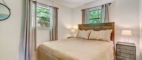 A bedroom with a wooden bed, a nightstand with a lamp, and a ceiling fan.