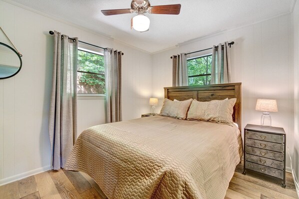 A bedroom with a wooden bed, a nightstand with a lamp, and a ceiling fan. - 3BR cabin with hot tub, mtn views, nearby lake access; near Tail of the Dragon; free rafting & train (Robbinsville)