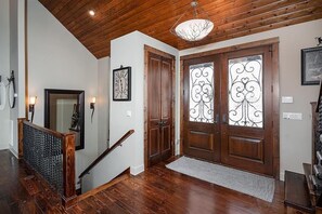 A wooden staircase with a handrail, a wooden door with decorative glass panels, and a chandelier. - Fontana Lake Lodge: 4BR/4BA lakefront home with hot tub, private dock, game room (Bryson City)