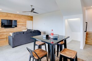 A modern living room with a sofa, a dining table with chairs, a ceiling fan, and a television mounted on the wall. - 3BR mountain-modern cabin with exceptional views, fireplace, and fire pit. Free rafting train passes (Bryson City)