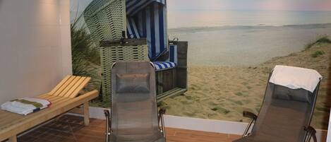 A room with two reclining chairs, a wooden bench, and a beach mural.