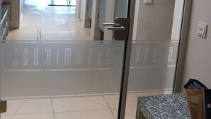Hotellin aula, jossa on lasiovi, laatoitettu lattia ja penkki.