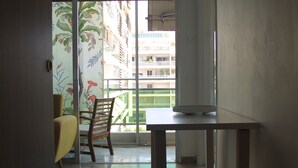 A room with a wooden table, a chair, a window with a view of buildings, and a door.