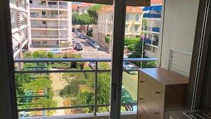 A balcony with a view of a residential area, a tiled floor, and a kitchenette with cabinets and a sink.