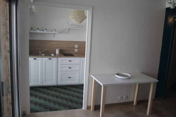 Une cuisine moderne avec des meubles blancs, un plan de travail en bois et une petite table sur laquelle se trouve un saladier.