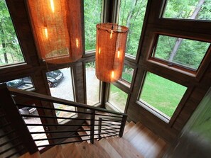 A wooden staircase with a metal railing leading to a large window with multiple panes.