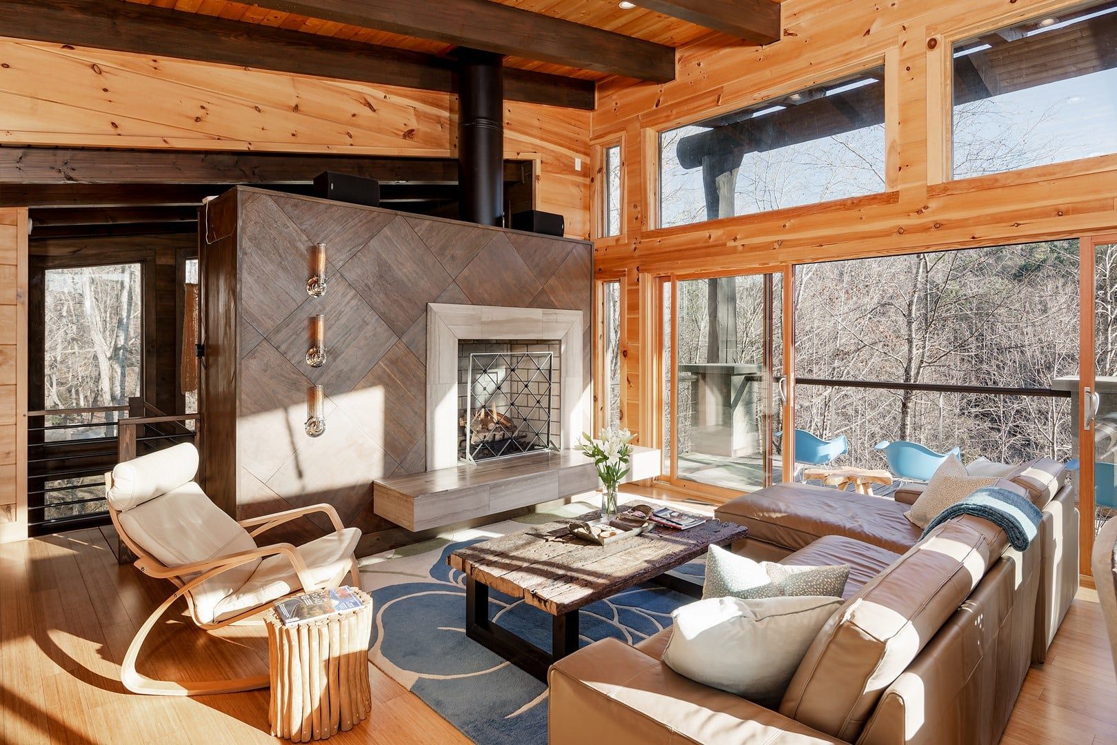 Una sala de estar acogedora con chimenea, paredes de madera y ventanas grandes.
