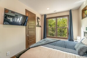 A bedroom with a bed, a television mounted on the wall, a window with curtains, and a door. - 3BR amazing view, hot tub, modern luxury sleeps 6 + railroad and rafting tix free (Bryson City)