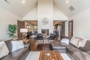 A spacious living room with a fireplace, leather sofas, a coffee table, and a dining area with chairs. - 3BR amazing view, hot tub, modern luxury sleeps 6 + railroad and rafting tix free (Bryson City)