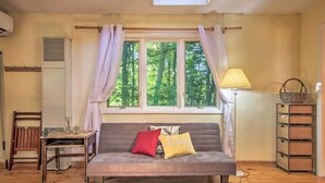 A cozy room with a sofa, a table, a lamp, and a window with curtains. - Quiet Saugatuck Studio w/ Patio - Walk to Dtwn! (Saugatuck)