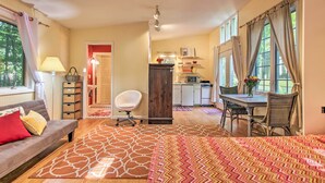 A cozy living room with a sofa, a dining table with chairs, a kitchen area, and a large window with curtains. - Quiet Saugatuck Studio w/ Patio - Walk to Dtwn! (Saugatuck)