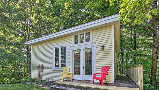 A small, single-story house with a front porch, two windows, and a sliding glass door. - Quiet Saugatuck Studio w/ Patio - Walk to Dtwn! (Saugatuck)