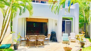 Un patio con muebles de mimbre, una parrilla y plantas en macetas.