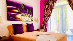 Una habitación de hotel con cama, almohadas, un cuadro, lámpara y cortinas.