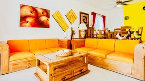 A living room with a wooden coffee table, orange sofa, and a ceiling fan. - Dolce Vita Caribe Executive Triple Room with Pool – Self Check-in - Playacar (Playa del Carmen)