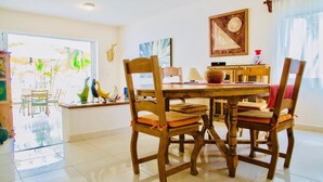 A dining area with a wooden table and chairs, a window with decorative items, and a painting on the wall.