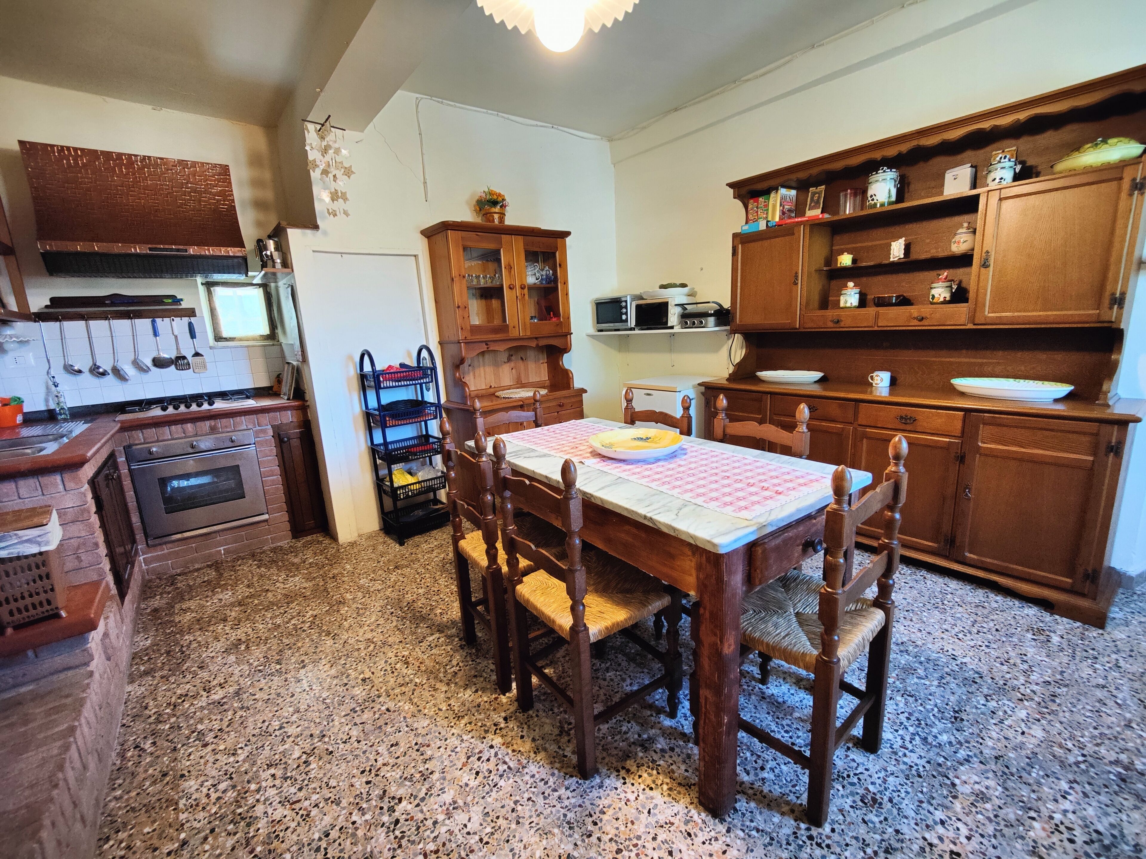 A kitchen with a wooden table, chairs, a stove, cabinets, and a microwave.