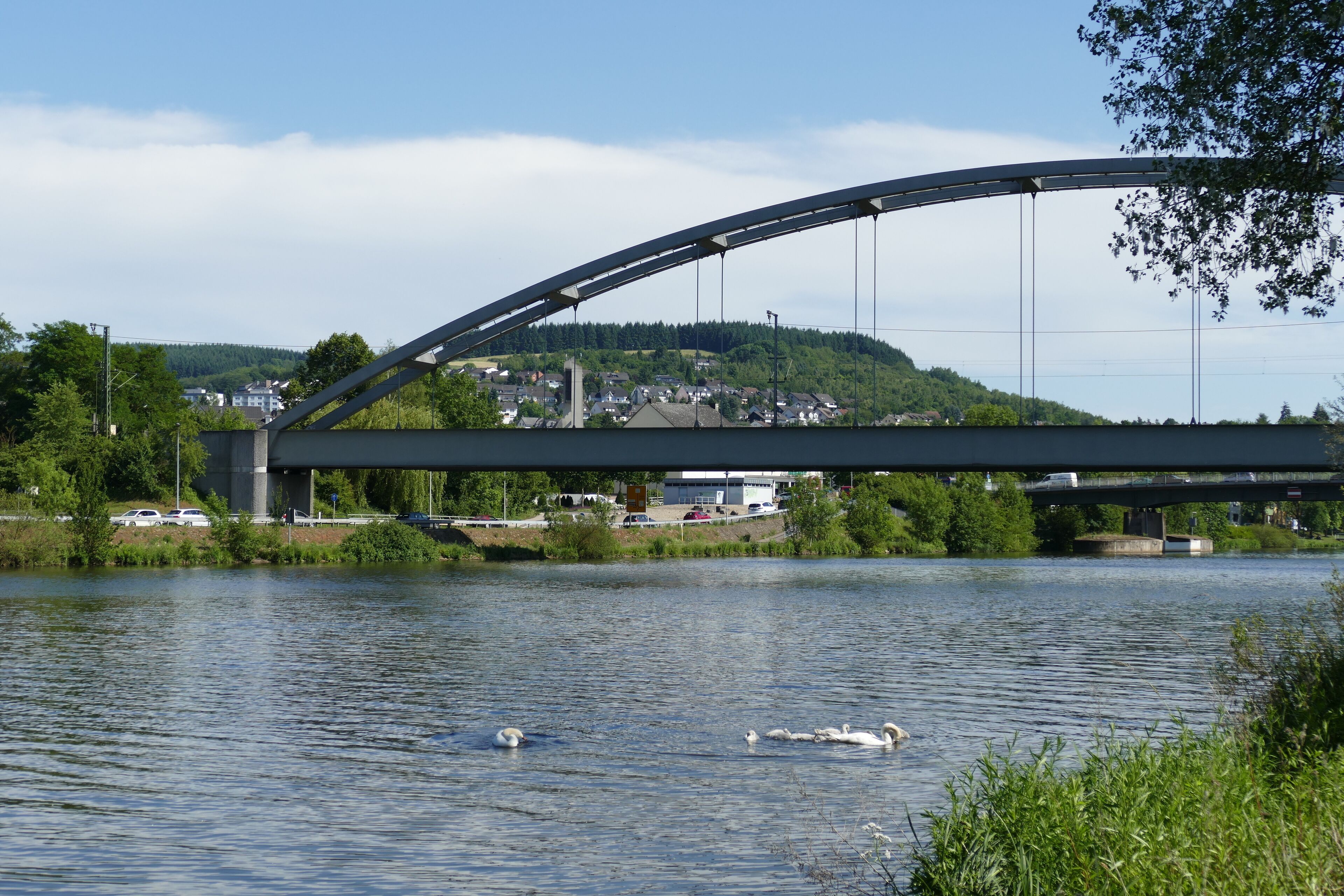 A bridge over a river with swans swimming in the water.