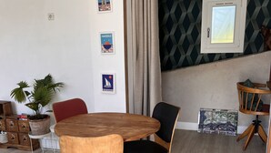 A dining area with a wooden table and chairs, a potted plant, and wall art. - Panoramic view of Marseille and sunset, calm, nature and garden (Marseille)